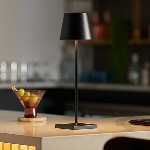 A black cordless rechargeable table lamp with a slim design and square base.