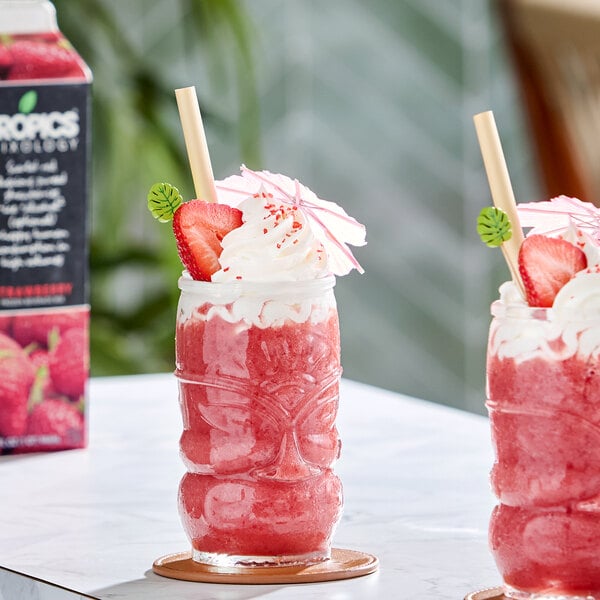 A glass of strawberry frozen beverage topped with whipped cream, a strawberry slice, and a decorative paper umbrella.