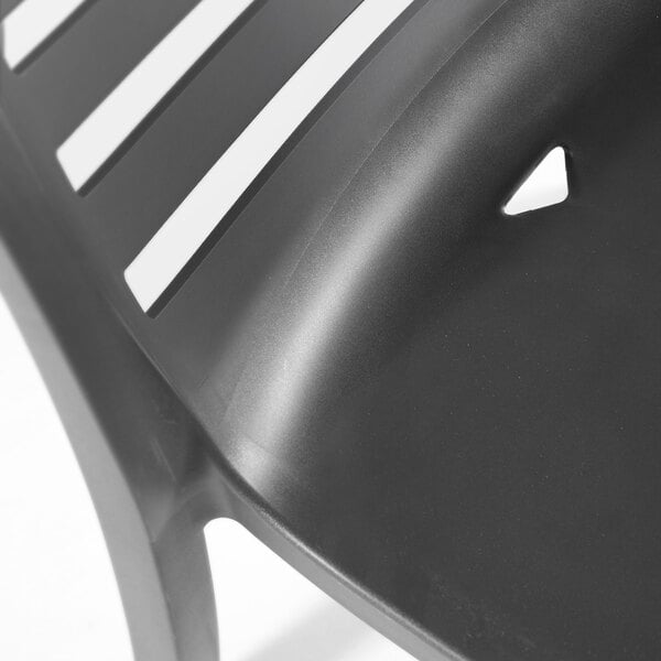 A charcoal-colored resin stackable outdoor side chair with a slatted back design.