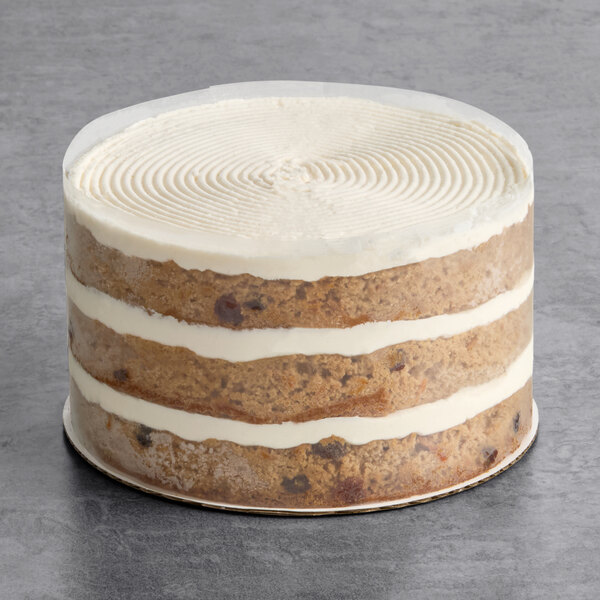 A round, four-layer vegan carrot cake with visible layers of white frosting and a smooth, undecorated top.