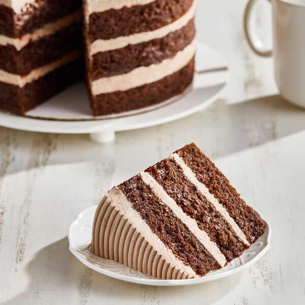 A slice of vegan chocolate layer cake with chocolate frosting, served on a white plate.