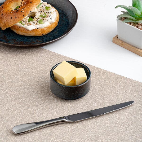 A small black round embossed porcelain ramekin filled with butter cubes.