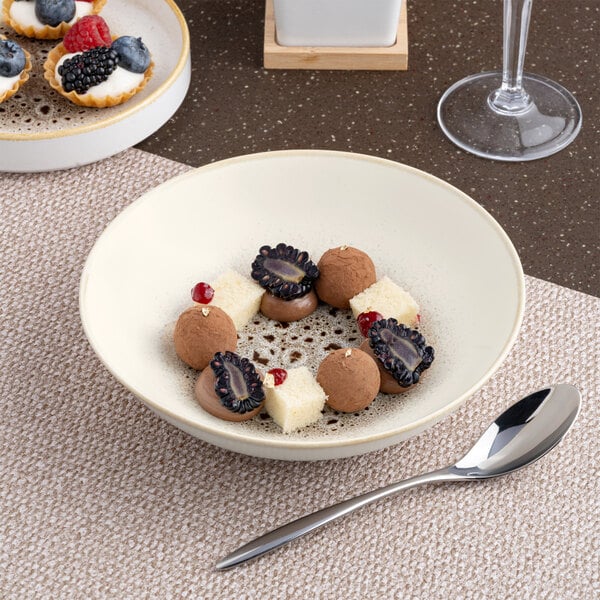 A round, deep coupe porcelain plate in brown and cream, shown with a dessert arrangement.