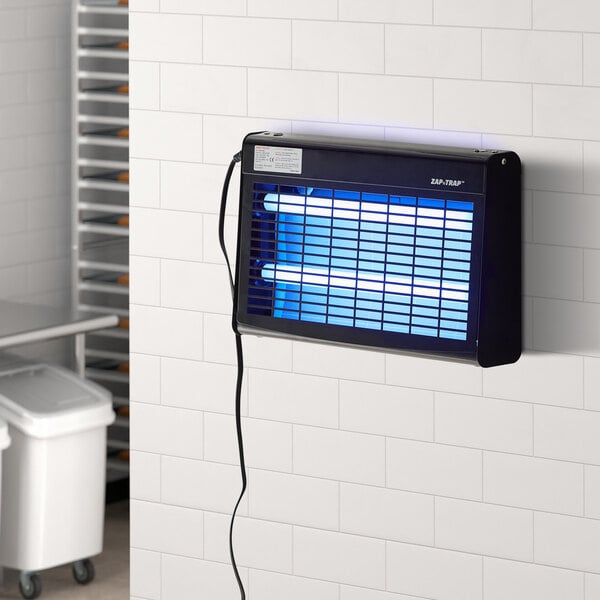 A black indoor LED insect light trap mounted on a tiled wall, designed for pest control.