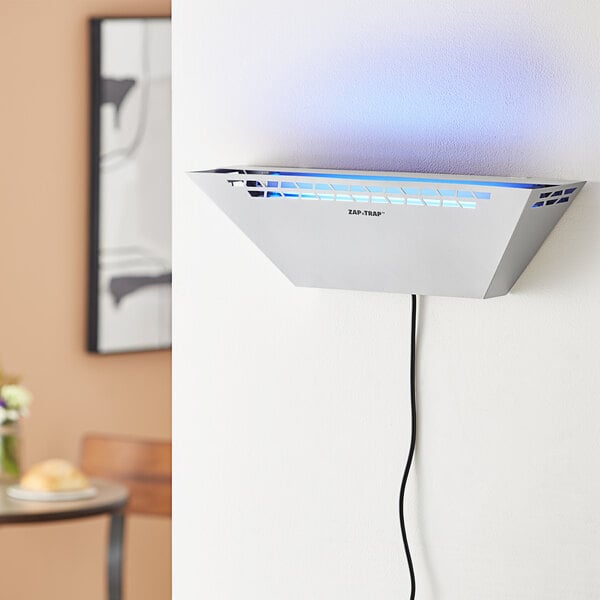 A silver metal trapezoidal wall-mounted LED insect light trap with a power cord.