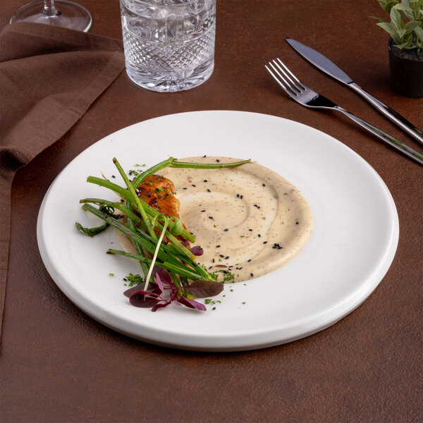A round ivory porcelain plate with a modern design, shown with a gourmet food presentation.