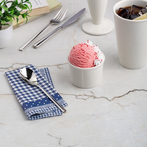 A small ivory round porcelain dessert bowl filled with pink ice cream and whipped cream.