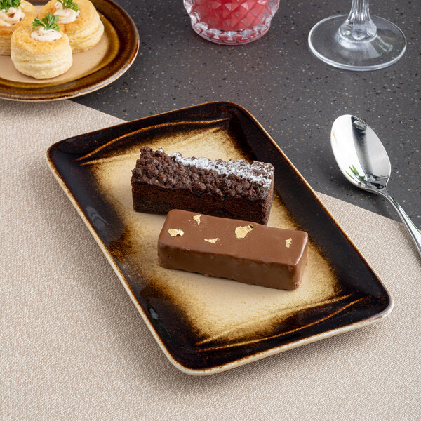 A brown rectangular porcelain platter with an embossed wide rim, shown holding two assorted desserts.