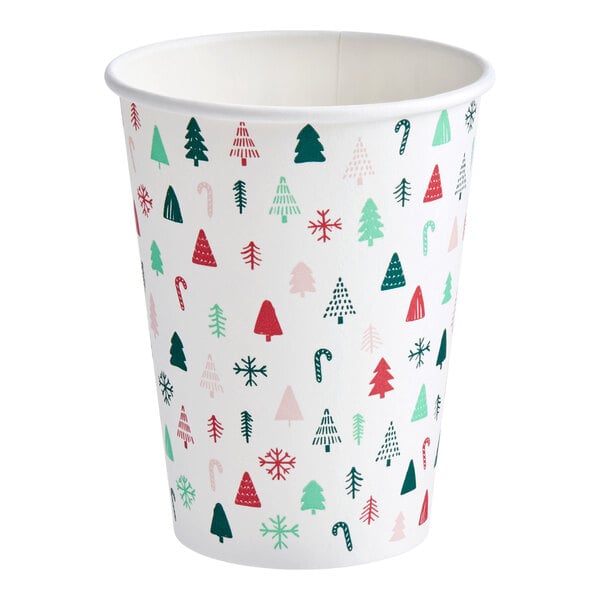A white paper hot cup with a modern Christmas print featuring trees, candy canes, and snowflakes in red, green, and pink.