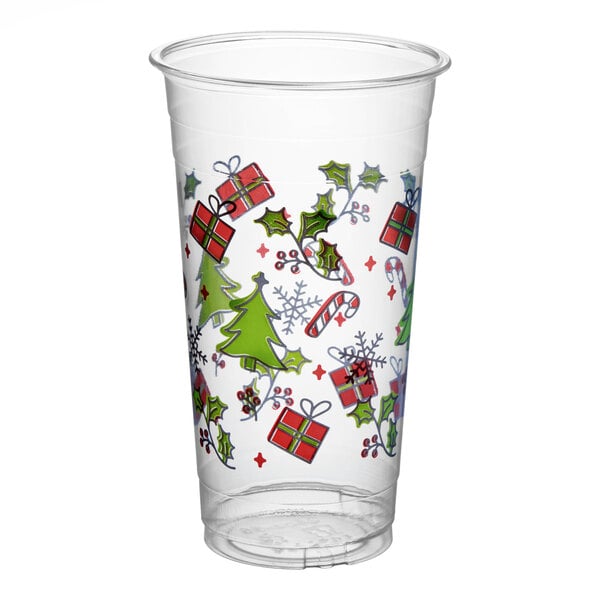 A clear plastic cup decorated with holiday-themed images such as Christmas trees, holly, presents, candy canes, and snowflakes.