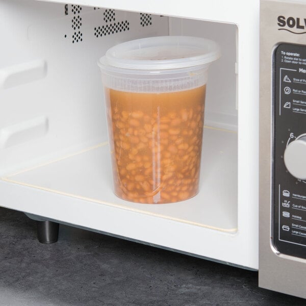 A translucent Pactiv deli container with beans in it in a microwave.