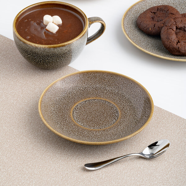 A brown round rimless porcelain tea cup saucer with a speckled pattern.