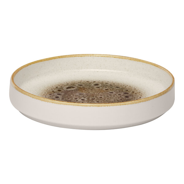 A round, cream-colored porcelain plate with a raised rim and a brown speckled center.
