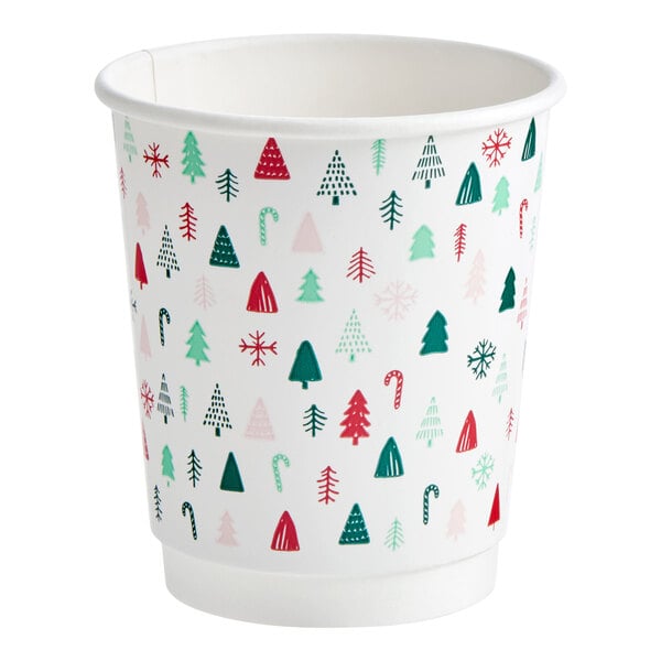 A white paper hot cup with a modern Christmas print featuring trees, candy canes, and snowflakes in red, green, and pink.