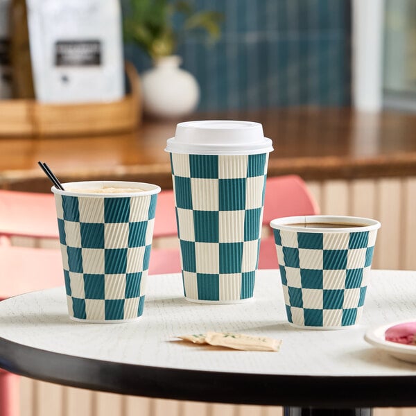 A set of navy and cream checkered double wall ripple paper hot cups in various sizes, with one featuring a white lid.