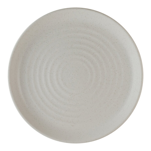 A round, light-colored porcelain plate with a subtle speckled pattern and concentric circular ridges.