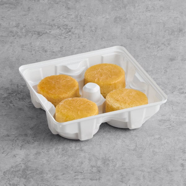 A white plastic tray containing four individual olive oil citrus cakes.