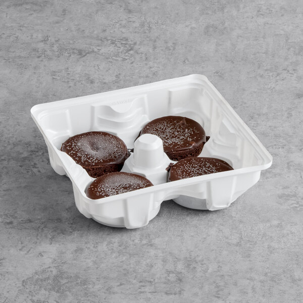 A white tray containing four individual flourless chocolate cakes topped with powdered sugar.