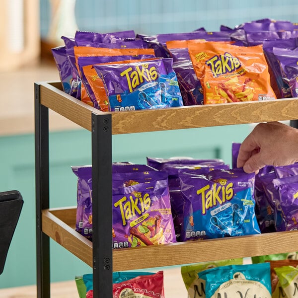 A display shelf with various flavors of Takis Rolled Tortilla Chips in small 1 oz. bags.