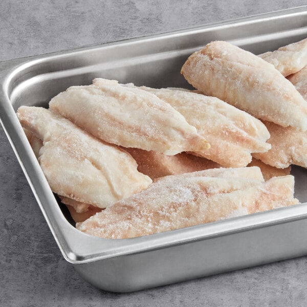 A stainless steel tray filled with frozen ocean perch fillets.