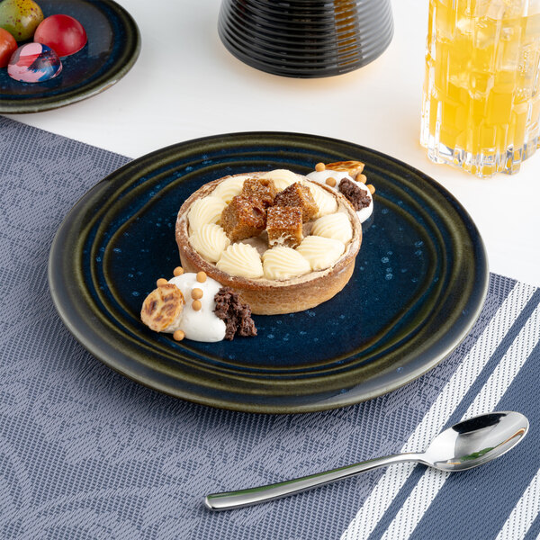 A blue round porcelain coupe flat plate with a dessert served on it.