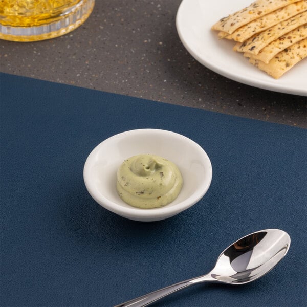 A small ivory round porcelain coupe bowl filled with a dollop of green sauce.