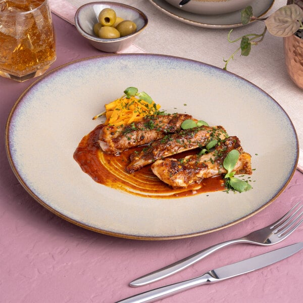 A beige round slanted porcelain coupe flat plate with a food presentation, shown on a table setting.