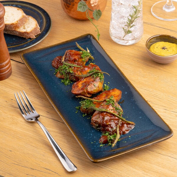A blue rectangular porcelain platter displaying a serving of glazed meat garnished with herbs.
