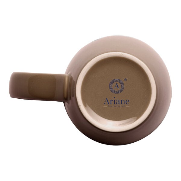 A beige porcelain mug shown from the bottom with the Ariane brand logo and text visible.