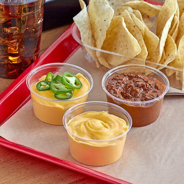A table with bowls of Muy Fresco cheddar cheese sauce and chips.