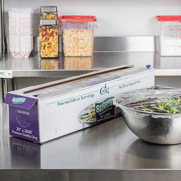 A box of Choice Safecut 24-inch by 2000-foot premium foodservice film with a slide cutter, shown in a commercial kitchen setting.
