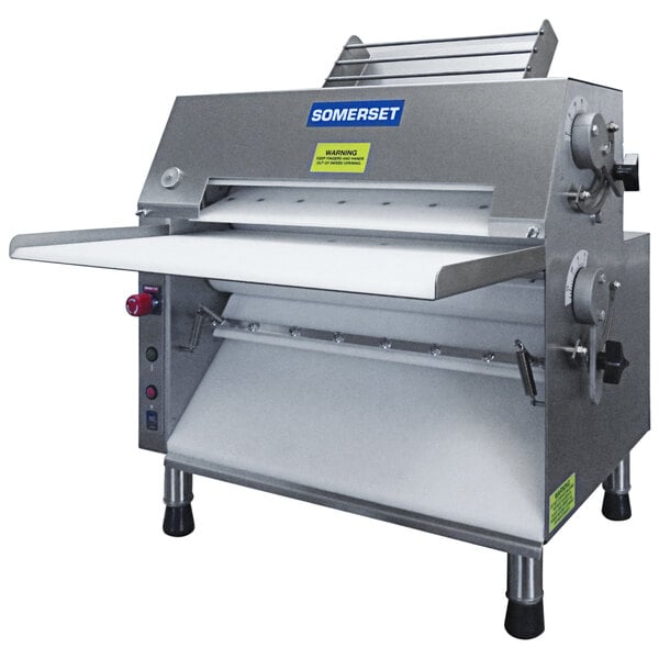 A commercial countertop dough sheeter with metallic rollers designed for flattening dough, featuring a front-operated design and labeled Somerset.