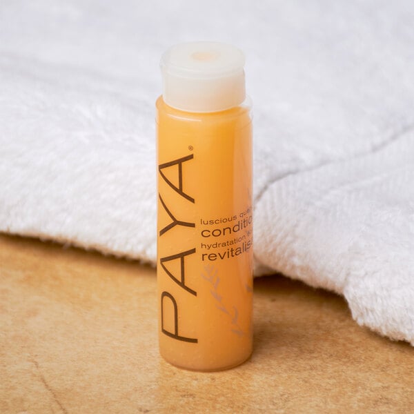A small bottle of PAYA papaya conditioner placed on a surface next to a white towel.