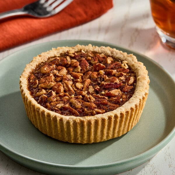 A small pecan pie with a golden crust and a nutty filling, served on a green plate.