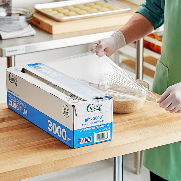 A large box of Choice 18-inch by 3000-foot foodservice cling film with a serrated cutter being used to cover a bowl.