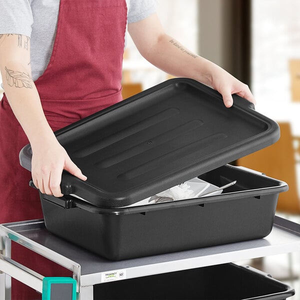 A black polyethylene bus tub lid being placed on a matching bus tub.