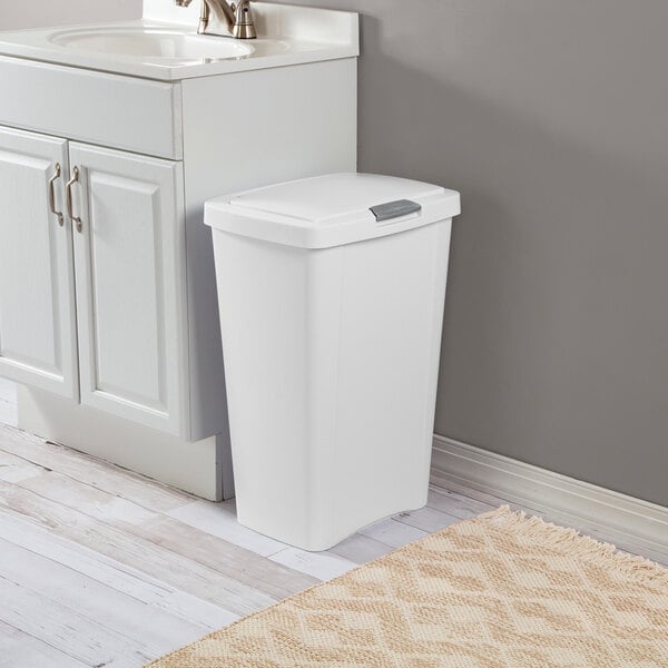 A white rectangular wastebasket with a lid placed next to a bathroom vanity.