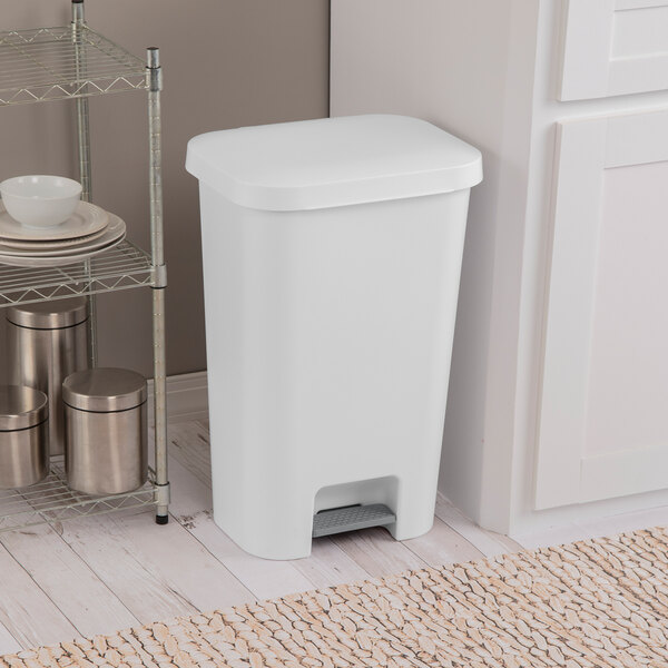A white rectangular step-on wastebasket placed in a kitchen setting.