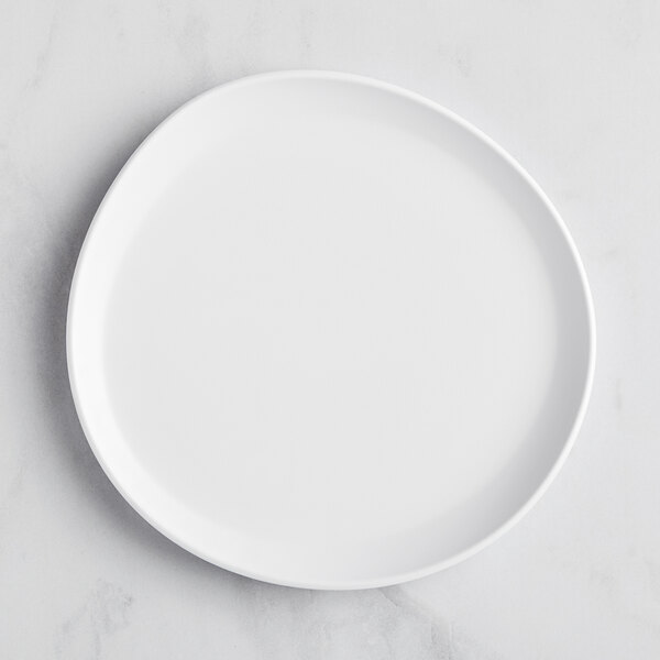 A white, irregular round matte melamine coupe plate.