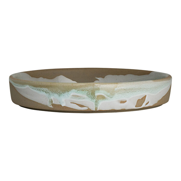 A round stoneware bowl with a beige base and white and green glaze accents.