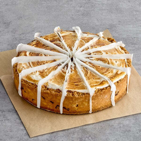 A round, pre-sliced s'mores cheesecake with a marbled top, placed on parchment paper.