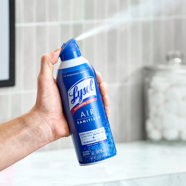 A can of Lysol White Linen Scent Air Sanitizer Spray being used in a bathroom setting.