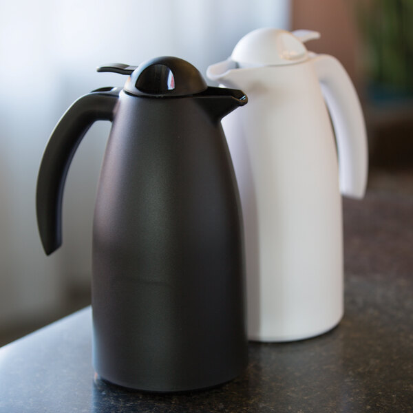 A black and a white plastic insulated coffee server with push-button lids.