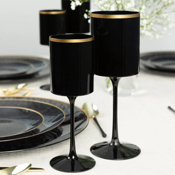 A set of black plastic wine goblets with gold rims displayed on a formal dining table.