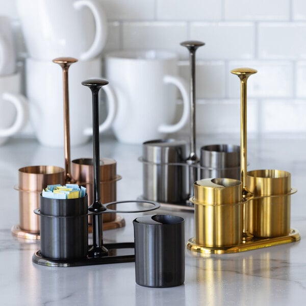 A rose gold stainless steel sugar stick holder and creamer set with a modern design.