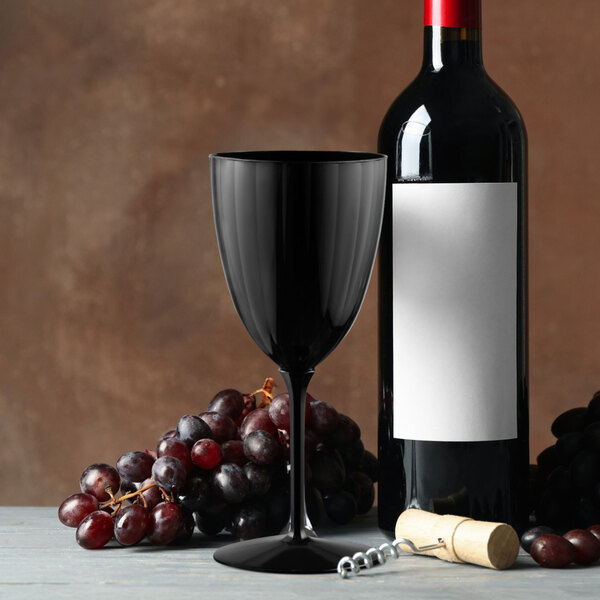 A black plastic wine goblet is displayed next to a wine bottle, grapes, and a corkscrew.