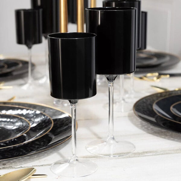 A set of two-toned black and clear plastic wine goblets arranged on a formal dining table.