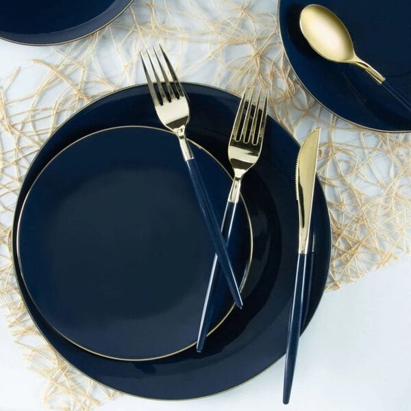 A set of navy blue round plastic plates with a gold band, accompanied by gold and navy cutlery.