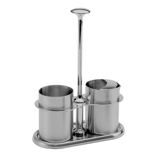 A stainless steel sugar stick holder and creamer set with a central handle.