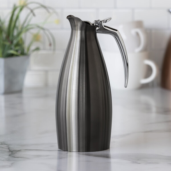 A dark tungsten stainless steel insulated coffee carafe server with a sleek, modern design and a curved handle.